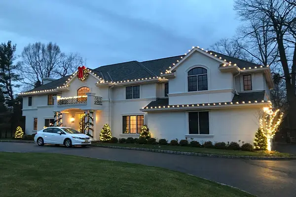 Elegant home adorned with Christmas lights, featuring a large bow and greenery, showcasing festive holiday spirit in Fresno, CA.